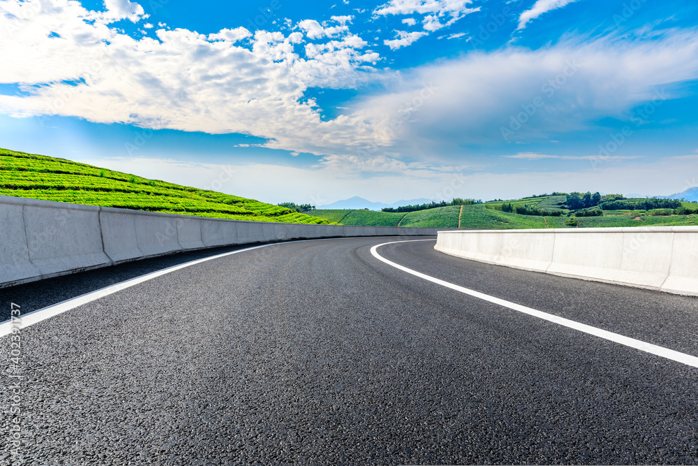 Fototapeta premium Asphalt road and mountain with tea plantation under blue sky.Road and mountain background.