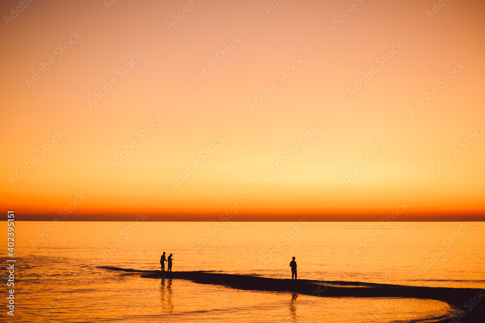 black silhouettes of people on the beach at sunset