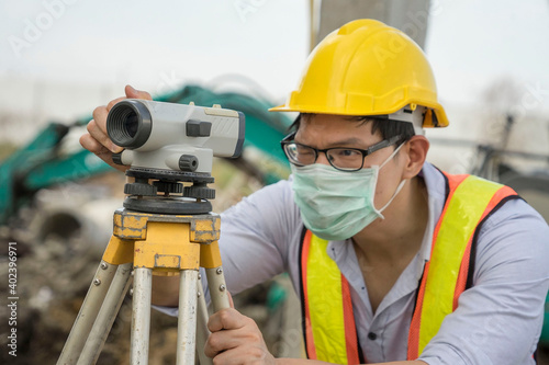 Asian chief foreman wearing an engineer hat to conduct land surveyor survey the land in a housing project.Construction and real estate concept.