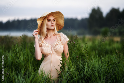 A beautiful girl stands in the tall grass and looks into the distance photo