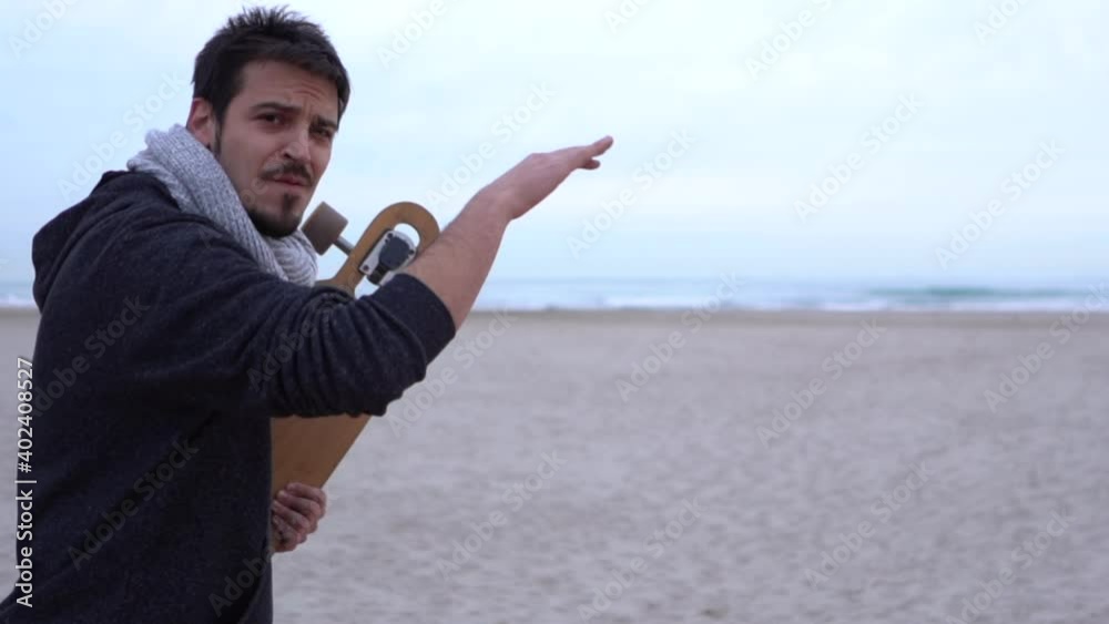 Surfer with longboard pointing to the sea and drawing waves with his hand Surfer with longboard pointing to the sea and drawing waves with his hand