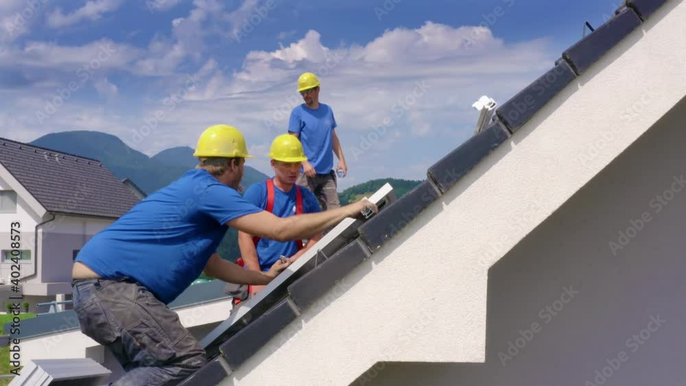 Workers Checking Solar Panel Installation On Roof. Aerial Side View Workers Checking Solar Panel Installation On Roof. Aerial Side View