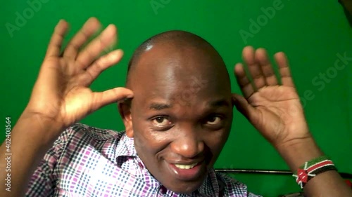 Close up of funny dark skinned man making hilarious gestures. Green screen in background. photo