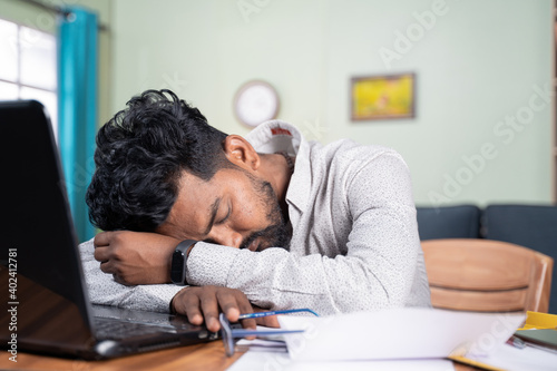 Young man got tired of working and slept on desk - Exhausted millennial fall asleep after after reading on laptop - Concept of napping at workplace and over work hours