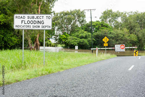 Warning sign road subject to flooding and now closed due to water over bridge. photo