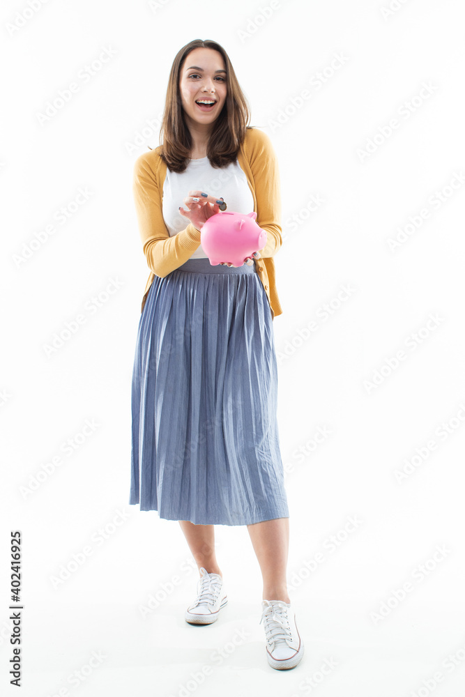 Young woman collects money in a pink piggy bank Young woman collects money in a pink piggy bank