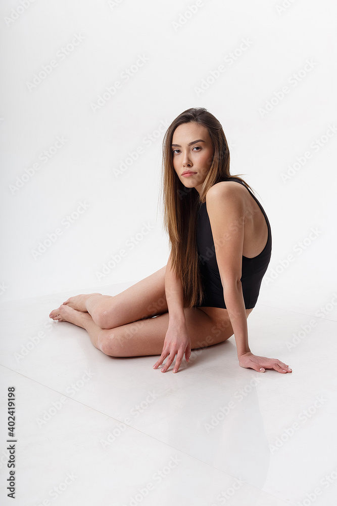 sexy asian woman with long hair posing in black lingerie on white studio background with bare feet. attractive female sitting on floor with her knees bent. model tests of skinny lady in bodysuit sexy asian woman with long hair posing in black lingerie on white studio background with bare feet. attractive female sitting on floor with her knees bent. model tests of skinny lady in bodysuit