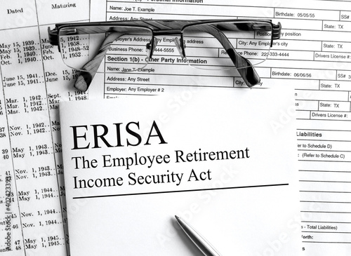 Paper with text ERISA on a financial table with eyeglasses and metal pen