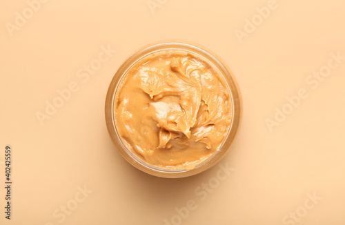 Bowl with tasty peanut butter on color background