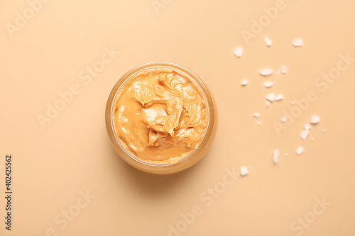 Bowl with tasty peanut butter on color background