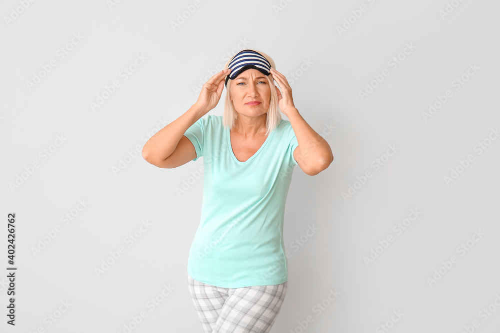 Mature woman in sleep mask on light background Mature woman in sleep mask on light background