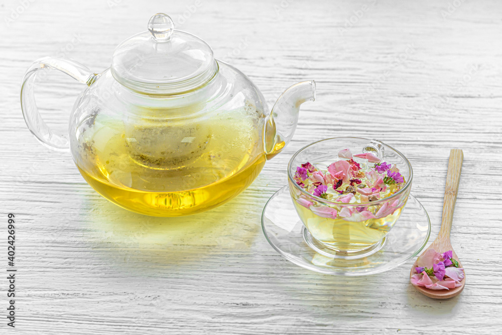 Teapot and cup with floral tea on light background Teapot and cup with floral tea on light background