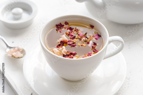 Cup with floral tea on light background