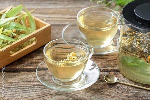 Teapot and cups with herbal tea on wooden background