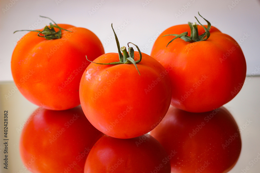 Several red tomatoes on a mirror surface Several red tomatoes on a mirror surface