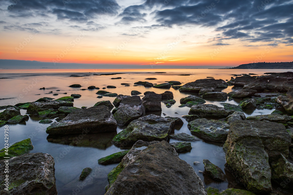 Colorful sunrise on the rocky sea coast, long exposure