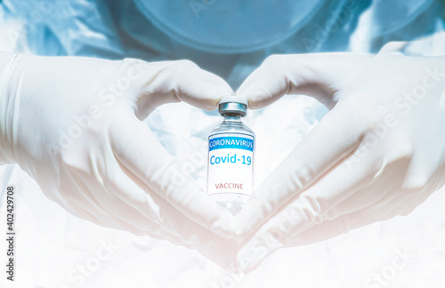 COVID-19 coronavirus vaccine with a vial in the hand wearing medical latex gloves form a heart shape. Virus destruction. Breakthrough in the creating and against coronavirus disease 2019 or COVID-19
