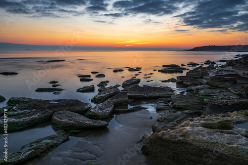 Colorful sunrise on the rocky sea coast, long exposure © Vastram