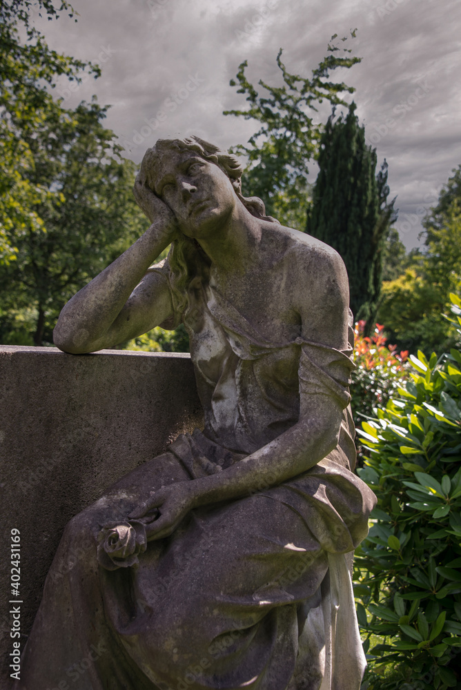 Naklejka premium eine Frau in tiefer Trauer lehnt an einem Grabstein