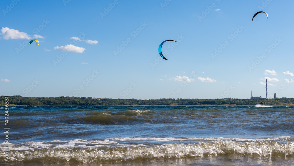 Kitesurfers flying over the lake. Kiteboarding (kitesurfing) during a