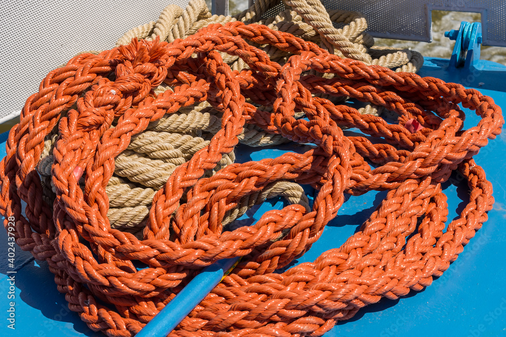 Two intertwined marine ropes on metal yacht deck. Sailboat equipment