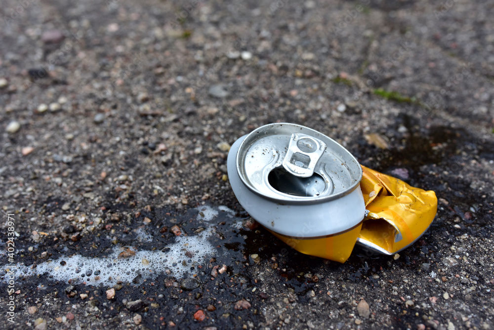 Crumpled a beer can on asphalt with spilled alcohol. Discarded broken carbonated drink can at a road. Problem social, crime. Environmental pollution, waste, ecology. Crushed juce. Out of focus Crumpled a beer can on asphalt with spilled alcohol. Discarded broken carbonated drink can at a road. Problem social, crime. Environmental pollution, waste, ecology. Crushed juce. Out of focus