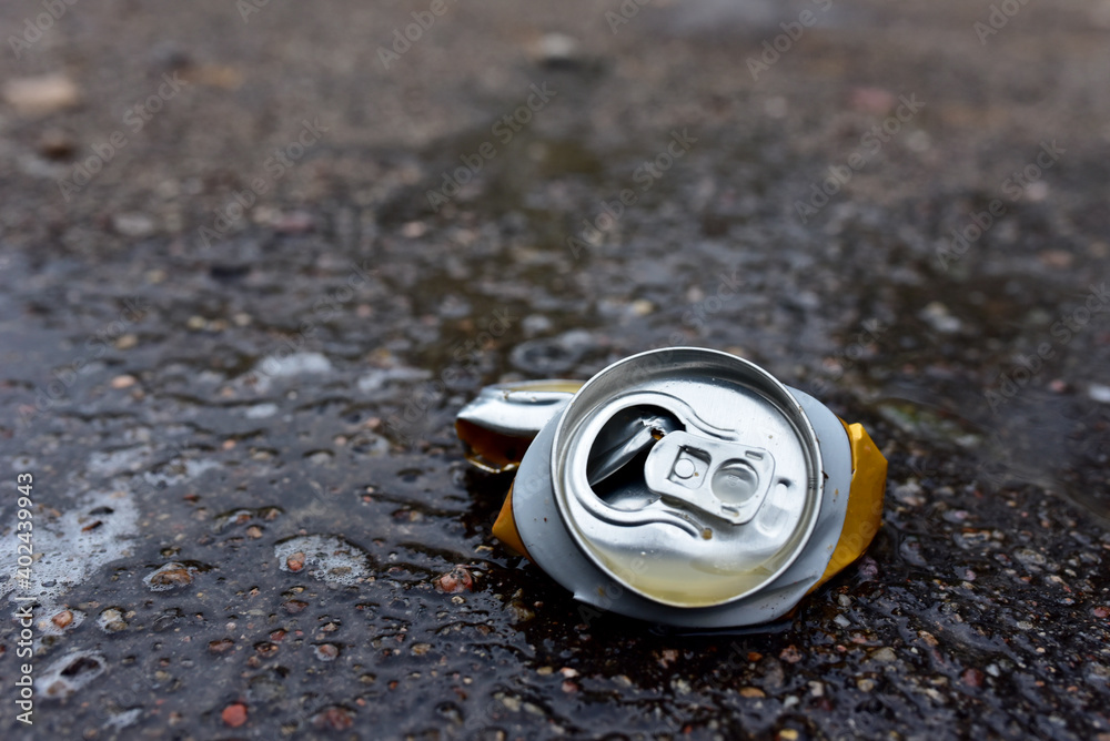 Crumpled a beer can on asphalt with spilled alcohol. Discarded broken carbonated drink can at a road. Problem social, crime. Environmental pollution, waste, ecology. Crushed juce. Out of focus Crumpled a beer can on asphalt with spilled alcohol. Discarded broken carbonated drink can at a road. Problem social, crime. Environmental pollution, waste, ecology. Crushed juce. Out of focus