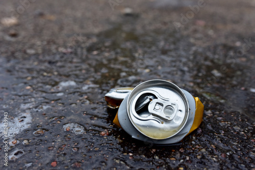 Crumpled a beer can on asphalt with spilled alcohol. Discarded broken carbonated drink can at a road. Problem social, crime. Environmental pollution, waste, ecology. Crushed juce. Out of focus