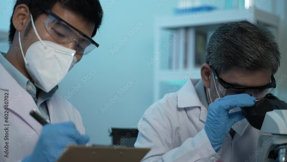 a scientist researching and analyzing results in the laboratory, holding and looking at a test tube while testing samples for the presence of coronavirus (COVID-19), applying the vaccine a scientist researching and analyzing results in the laboratory, holding and looking at a test tube while testing samples for the presence of coronavirus (COVID-19), applying the vaccine