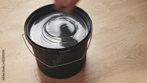 Stirring gray paint in a can. Preparing to paint the walls. Home apartment renovation.