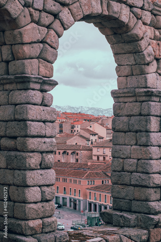 acueducto romano segovia españa ciuda y montañas a traves del arco tonos naranjas marrones photo