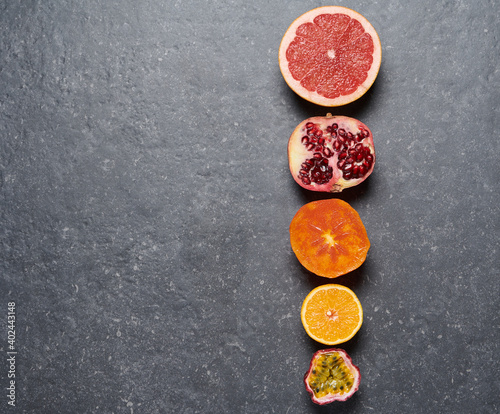 Line of orange, grapefruit, pomegrade, passion fruit and kaki on grey background