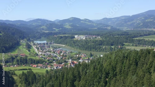 Aerial approaching charming town by river surrounded by forest and mountains photo