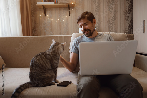 Young attractive smiling guy is browsing at his laptop