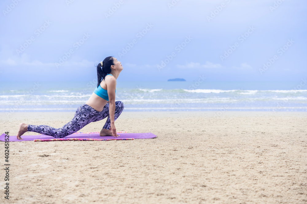 Adult Asian woman doing yoga on yoga mat at the beach Adult Asian woman doing yoga on yoga mat at the beach
