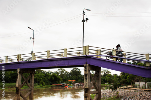Life of thai people walking biking bicycle and riding motorcycle on small bridge cross Sakae Krang river go to Uthaithani city and local market in Uthai Thani Province of Thailand