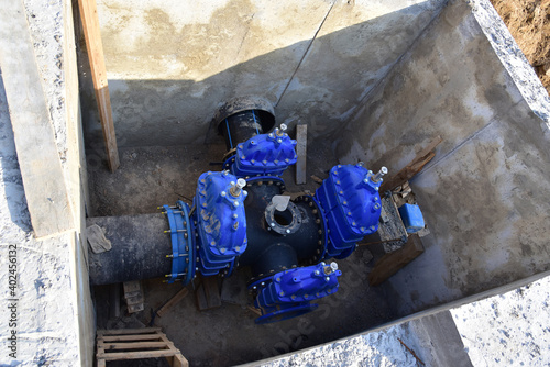 Resilient Seated Gate Valves connect pipeline of water supply in concrete bunker at constructin site. Solutions for drinking water and sewage. Valve pit of the system underground piping networks. photo