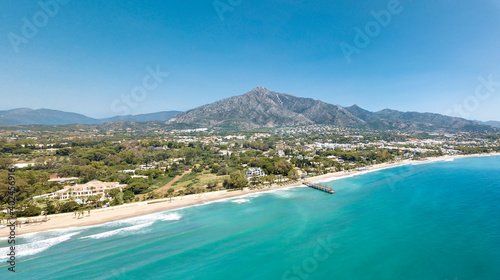 Unique aerial view of luxury and exclusive area in Marbella, golden mile beach, view of Puente Romano Bridge and in background famous La Concha mountain. Emerald water colour 