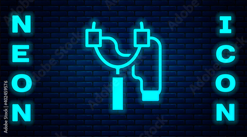 Glowing neon Slingshot icon isolated on brick wall background. Vector.