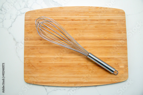 Metal whisk on a wooden cutting board