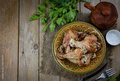 Hearty lunch: Chicken legs baked in milk on a plate on a wooden table