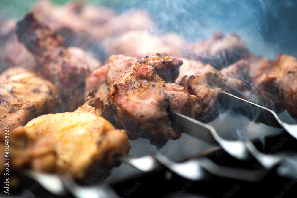 Shashlik or shish kebab preparing on barbecue grill over hot charcoal. Grilled pieces of pork meat on metal skewers. Shashlik or shish kebab preparing on barbecue grill over hot charcoal. Grilled pieces of pork meat on metal skewers.