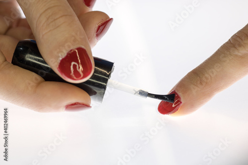A woman applying red nail polish.