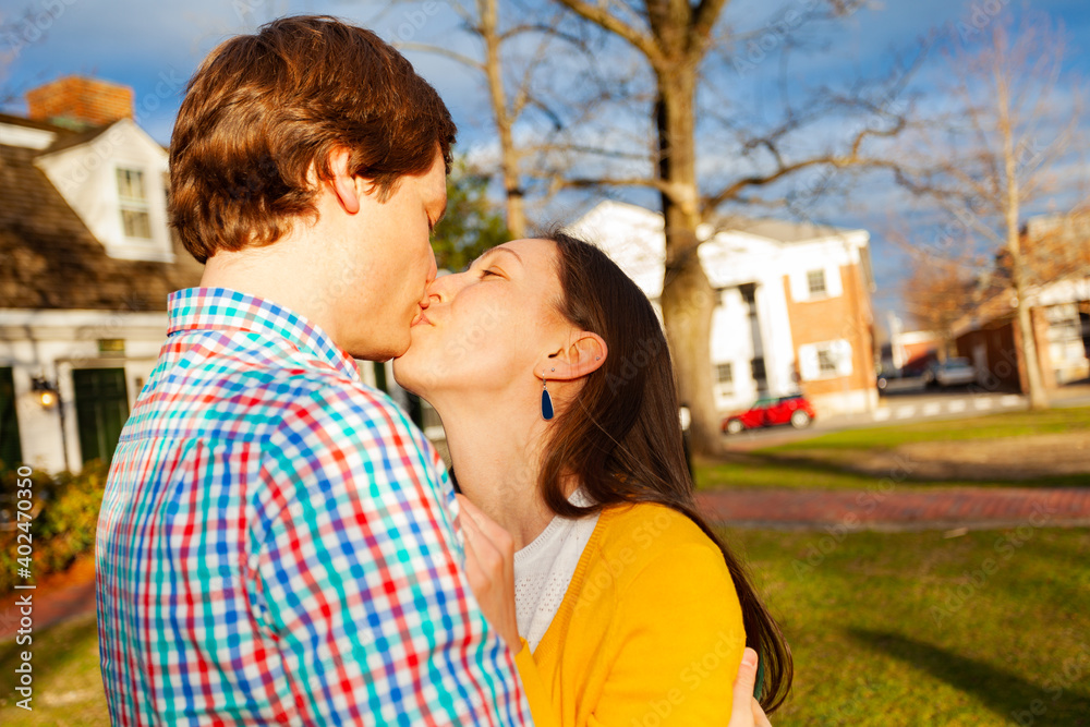 Obraz premium Young happy couple kiss close portrait stand in public park profile view
