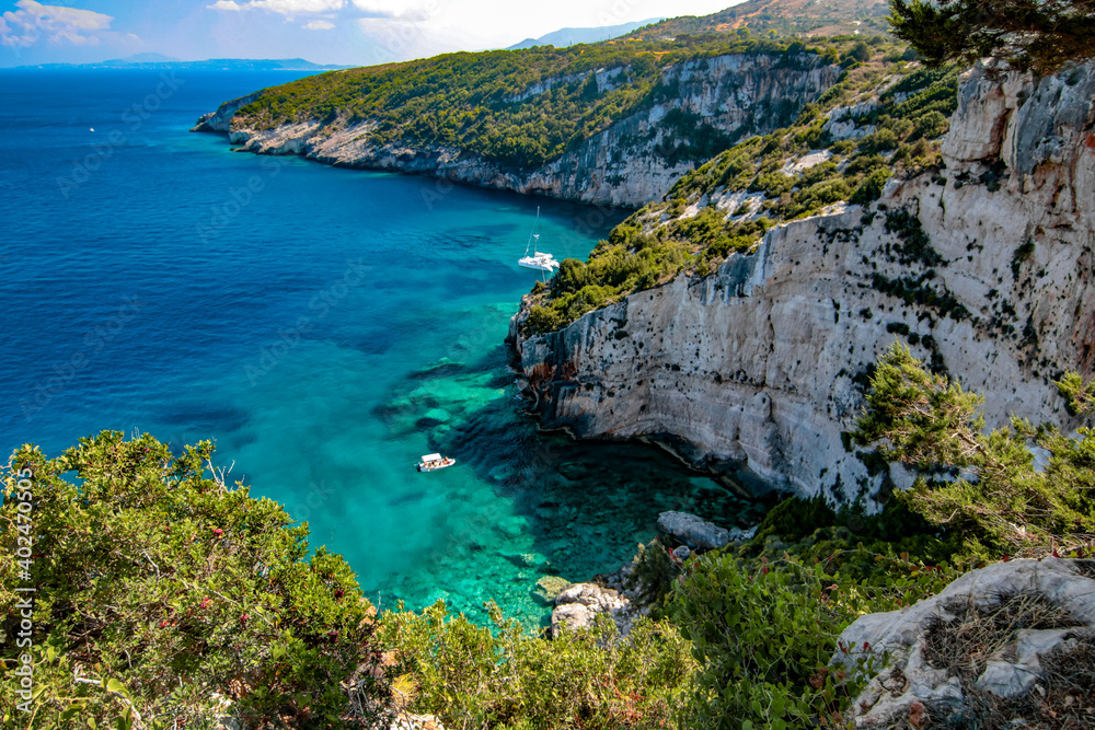 view of the coast on the Greek island of Zakynthos. The sea is clear blue and the sky blue with white clouds.