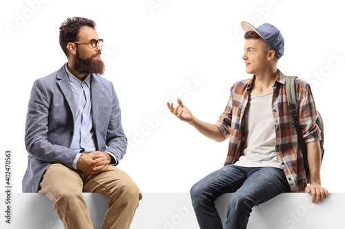 Fototapeta Naklejka Na Ścianę i Meble -  Man and a teenage male student sitting on a panel and talking
