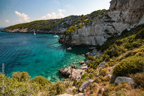 view of the coast on the Greek island of Zakynthos. The sea is clear blue and the sky blue with white clouds. © Tereza
