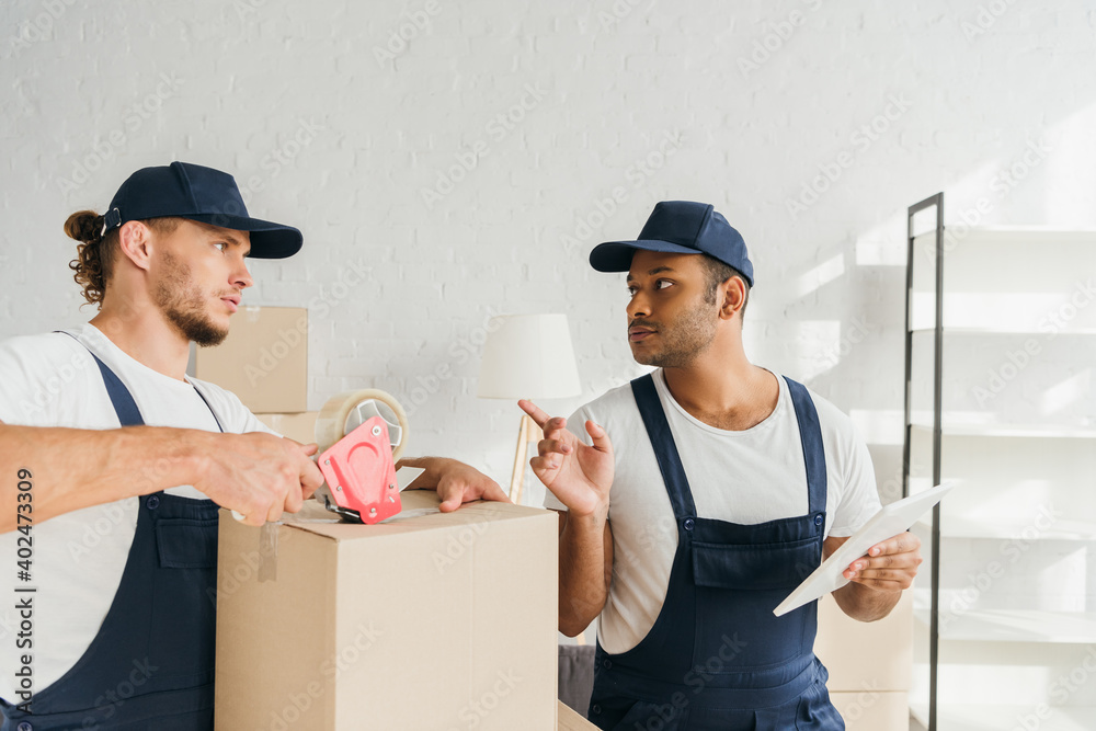 mover packing box near indian coworker pointing with finger and digital tablet mover packing box near indian coworker pointing with finger and digital tablet