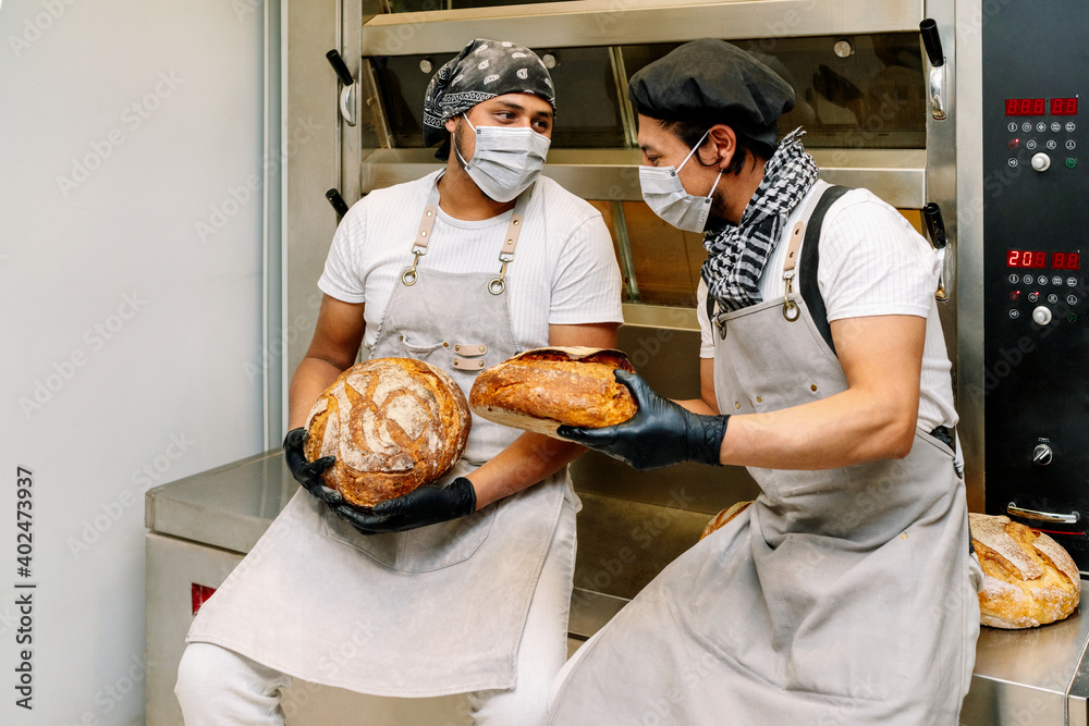 two happy latino bakers showing how they made a loaf of wheat bread in