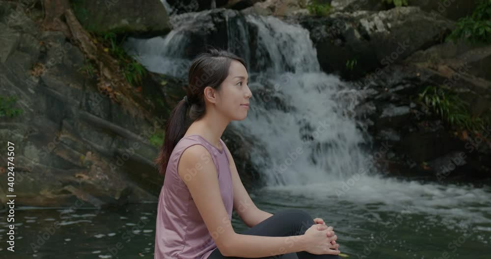 Sport woman sit beside waterfall Sport woman sit beside waterfall